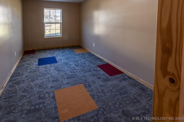 unfurnished room featuring dark carpet