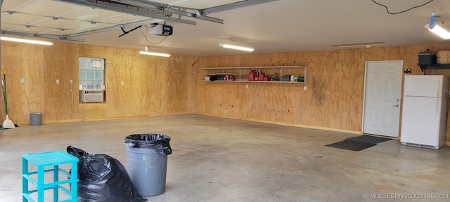 garage featuring wood walls, white fridge, a garage door opener, and cooling unit