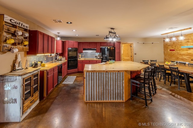 kitchen with butcher block counters, sink, hanging light fixtures, and black appliances