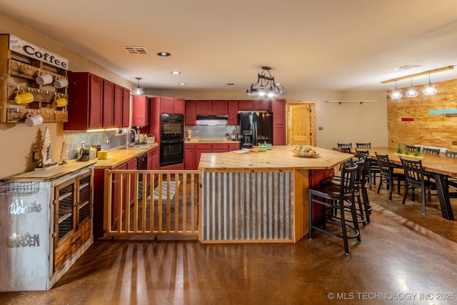 kitchen with butcher block counters, hanging light fixtures, black appliances, and sink