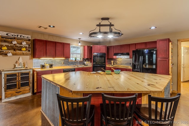 kitchen with wood counters, decorative light fixtures, a kitchen island, range hood, and black appliances