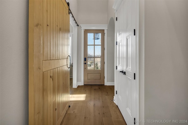 doorway to outside with a barn door and light hardwood / wood-style flooring