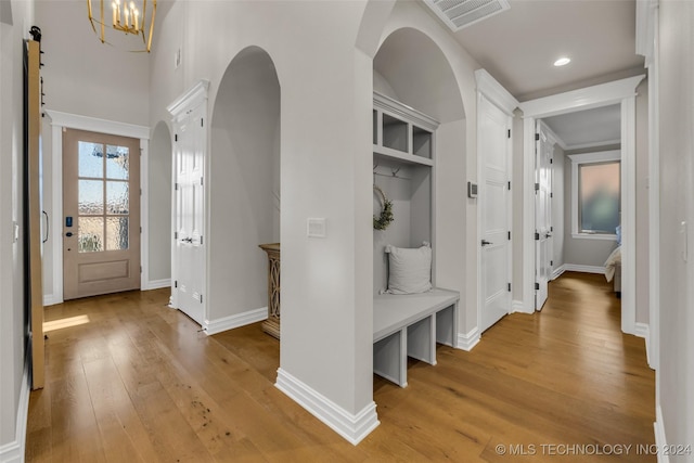 mudroom featuring light wood-type flooring and a chandelier