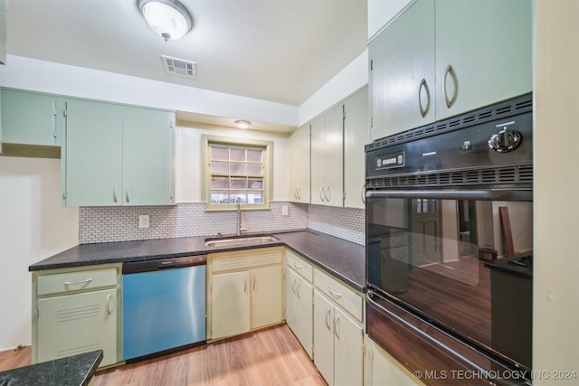 kitchen featuring dishwasher, sink, light wood-type flooring, and backsplash