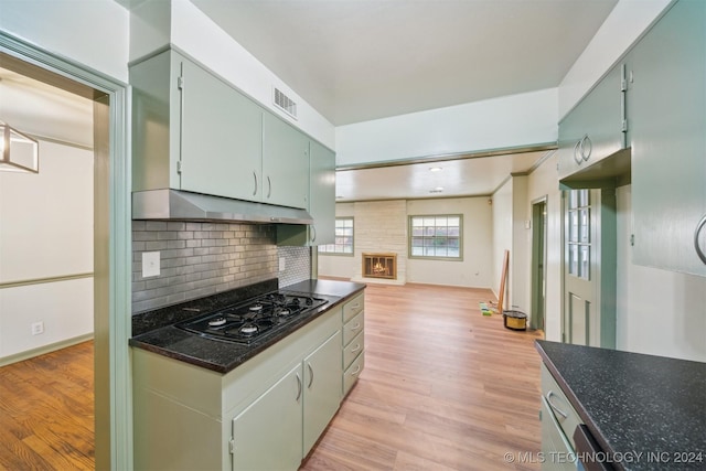 kitchen with decorative backsplash, light hardwood / wood-style flooring, and black gas stovetop