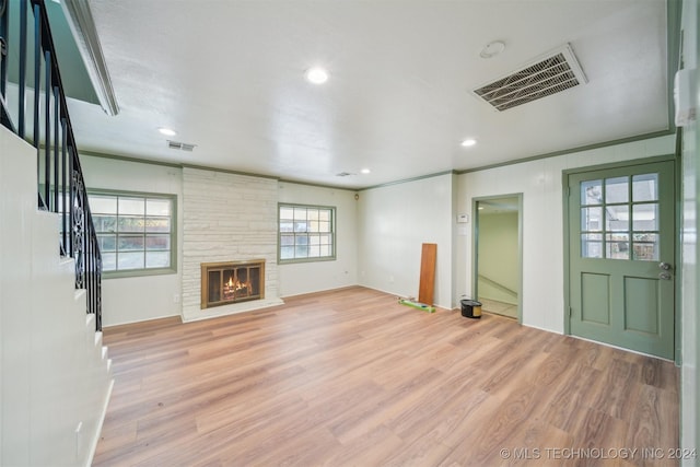 unfurnished living room with a fireplace, ornamental molding, and light wood-type flooring