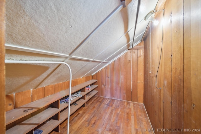 interior space featuring wooden walls, hardwood / wood-style floors, and vaulted ceiling