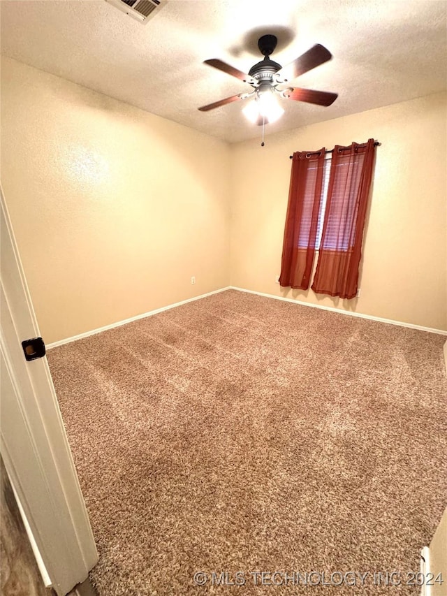 spare room featuring ceiling fan, carpet, and a textured ceiling