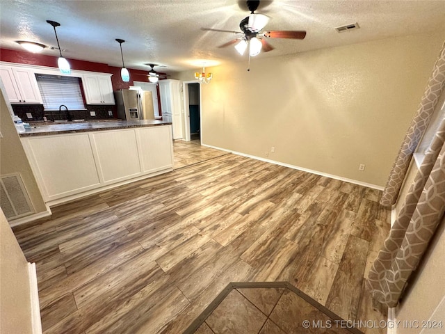 kitchen with tasteful backsplash, stainless steel fridge with ice dispenser, light hardwood / wood-style flooring, pendant lighting, and white cabinets