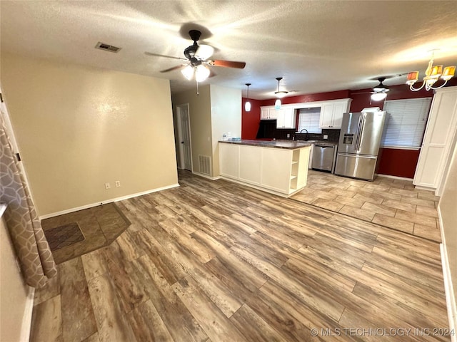 kitchen with stainless steel appliances, hanging light fixtures, kitchen peninsula, light hardwood / wood-style floors, and white cabinets