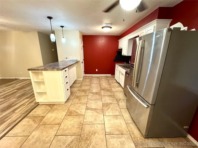 kitchen featuring white cabinets, stainless steel fridge, kitchen peninsula, and pendant lighting