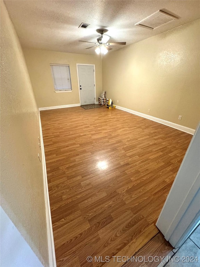 empty room with wood-type flooring, a textured ceiling, and ceiling fan