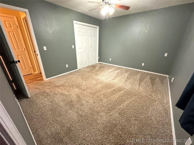 unfurnished bedroom featuring carpet flooring, ceiling fan, a textured ceiling, and a closet