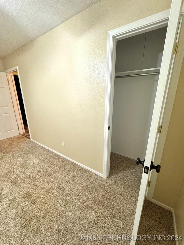 unfurnished bedroom with carpet flooring, a textured ceiling, and a closet