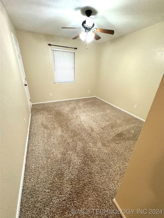 carpeted spare room featuring ceiling fan and a textured ceiling