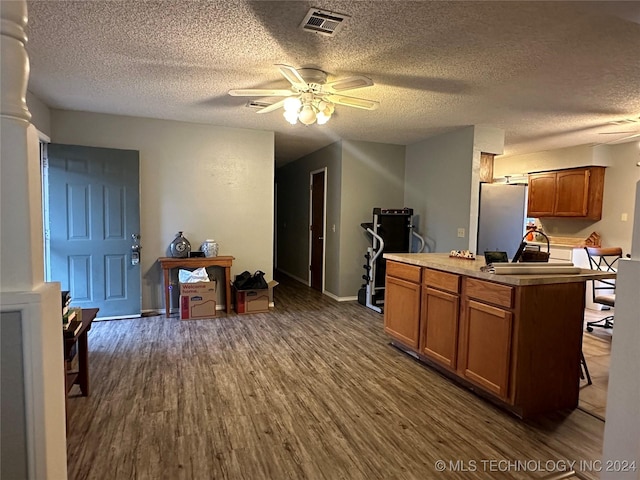 kitchen with ceiling fan, dark hardwood / wood-style flooring, a textured ceiling, and stainless steel refrigerator