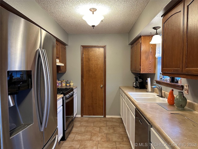 kitchen featuring pendant lighting, stainless steel appliances, a textured ceiling, and sink