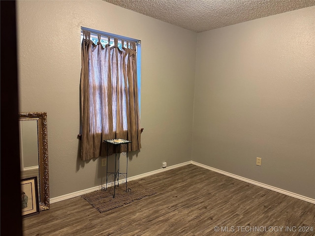 empty room with a textured ceiling and dark hardwood / wood-style floors