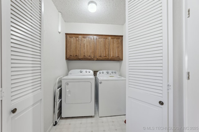 laundry room with a textured ceiling, cabinet space, light floors, and washing machine and clothes dryer