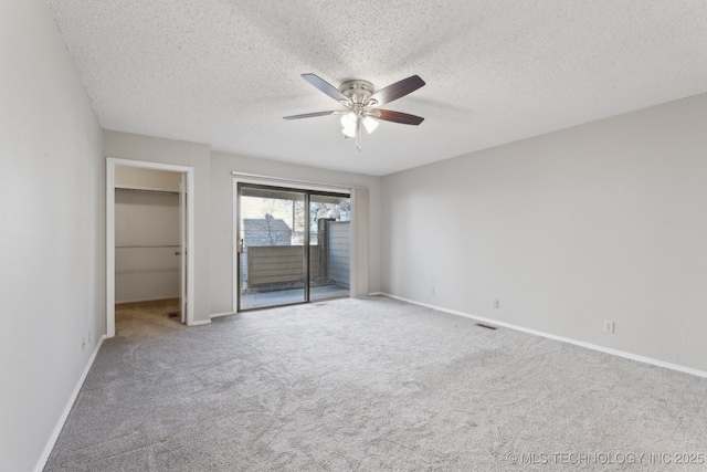 unfurnished bedroom with baseboards, ceiling fan, a walk in closet, access to outside, and carpet flooring