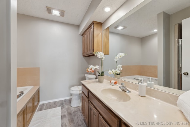 bathroom with visible vents, vanity, wood finished floors, a bath, and a textured ceiling