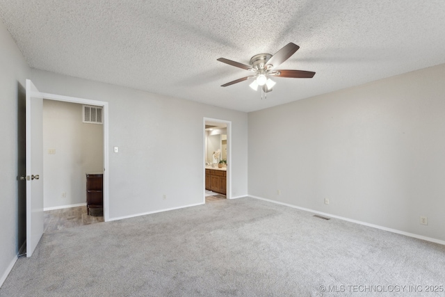 unfurnished bedroom featuring visible vents, a textured ceiling, ensuite bathroom, and carpet floors