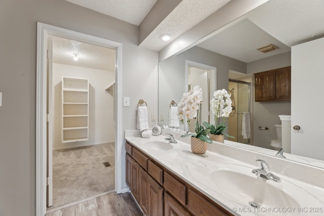 full bath featuring visible vents, a stall shower, a textured ceiling, and a sink