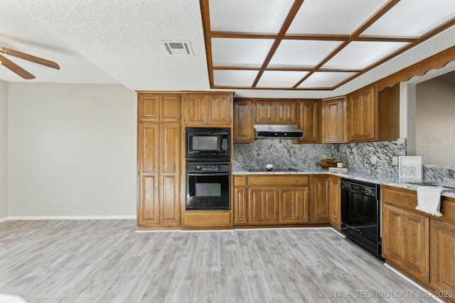 kitchen featuring visible vents, brown cabinets, black appliances, light wood-style flooring, and under cabinet range hood