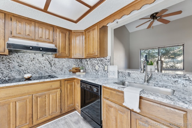 kitchen with under cabinet range hood, light stone counters, decorative backsplash, black appliances, and a sink