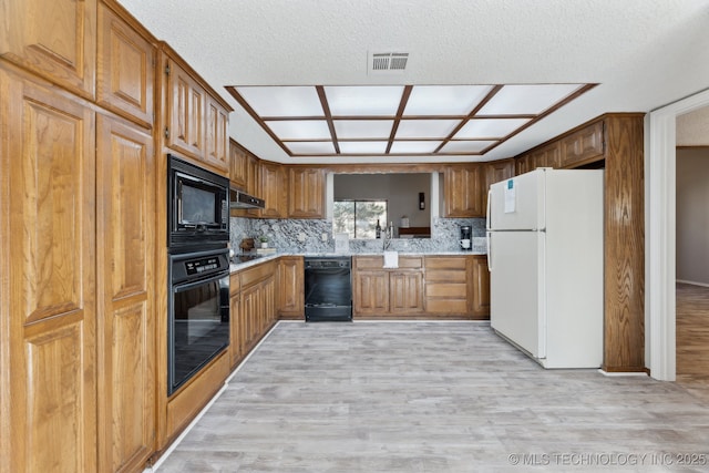 kitchen featuring visible vents, light wood-type flooring, light countertops, brown cabinets, and black appliances