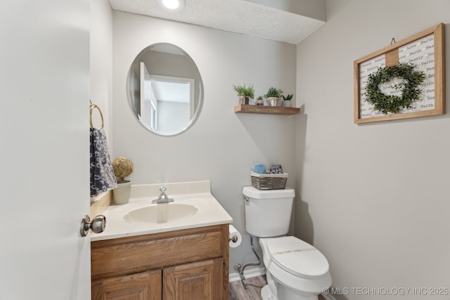 bathroom with toilet, a textured ceiling, wood finished floors, baseboards, and vanity