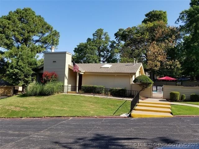 view of front of home featuring a chimney, a front yard, and fence