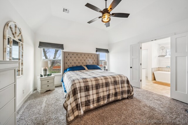 bedroom featuring light carpet, ensuite bathroom, vaulted ceiling, and ceiling fan