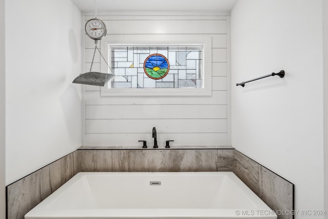 bathroom featuring a tub to relax in and wooden walls