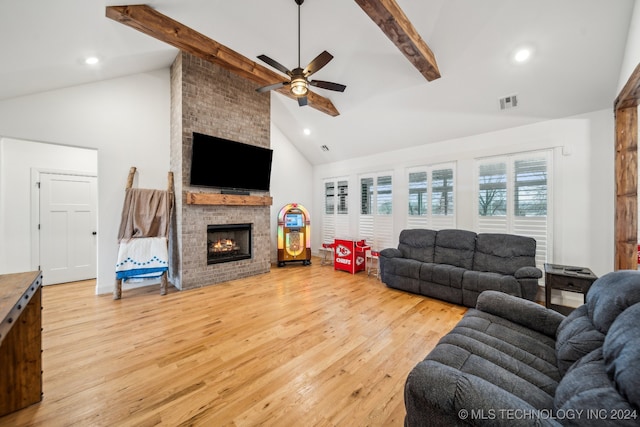 living room with high vaulted ceiling, hardwood / wood-style flooring, ceiling fan, a large fireplace, and beam ceiling