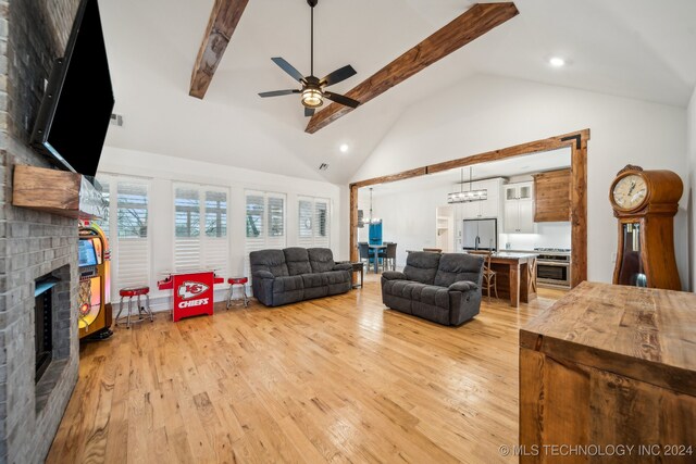 living room featuring light wood-type flooring, a fireplace, ceiling fan, high vaulted ceiling, and beamed ceiling