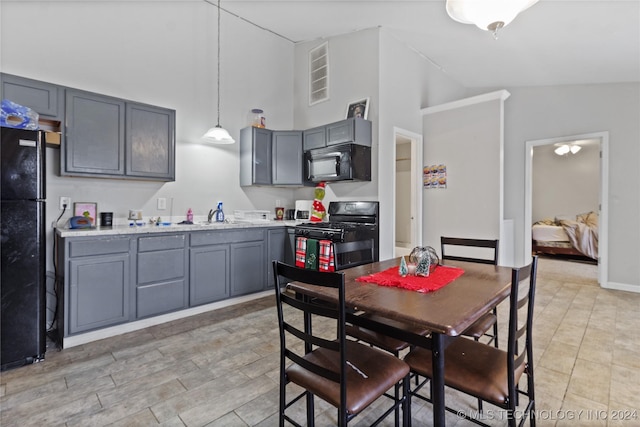 kitchen with gray cabinetry, sink, black appliances, hanging light fixtures, and lofted ceiling