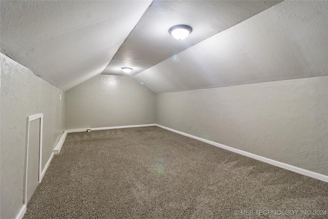 bonus room featuring a textured ceiling, carpet floors, and lofted ceiling