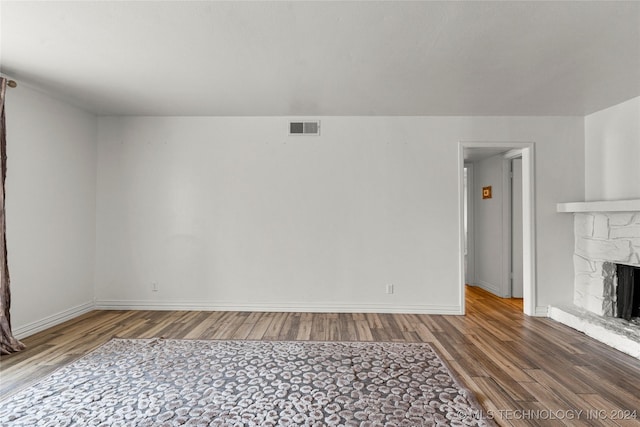 unfurnished living room with a stone fireplace and hardwood / wood-style flooring