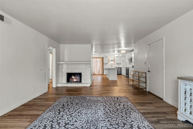 living room featuring dark hardwood / wood-style flooring and a stone fireplace