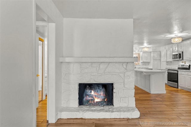 details with hardwood / wood-style floors, decorative backsplash, a fireplace, and appliances with stainless steel finishes