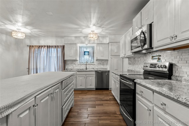 kitchen featuring stainless steel appliances, dark wood-type flooring, sink, a notable chandelier, and white cabinets