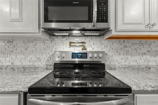 kitchen with decorative backsplash, white cabinetry, light stone countertops, and appliances with stainless steel finishes