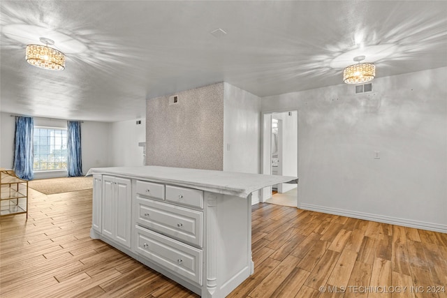 kitchen featuring a notable chandelier, light hardwood / wood-style floors, white cabinetry, and a breakfast bar area