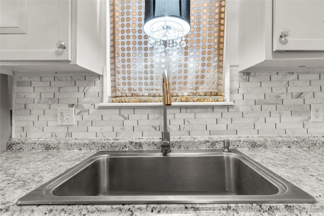 kitchen featuring backsplash, light stone countertops, sink, and white cabinets