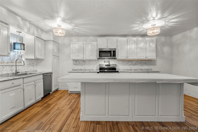 kitchen with white cabinetry, light hardwood / wood-style flooring, a kitchen island, and stainless steel appliances