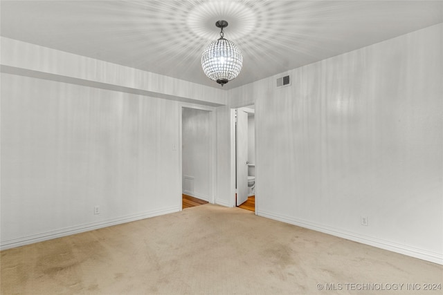 carpeted empty room with a notable chandelier