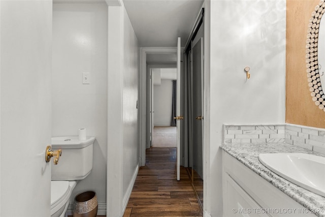 bathroom with hardwood / wood-style flooring, vanity, toilet, and backsplash