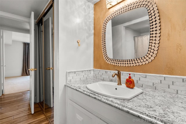 bathroom with hardwood / wood-style floors, vanity, and crown molding