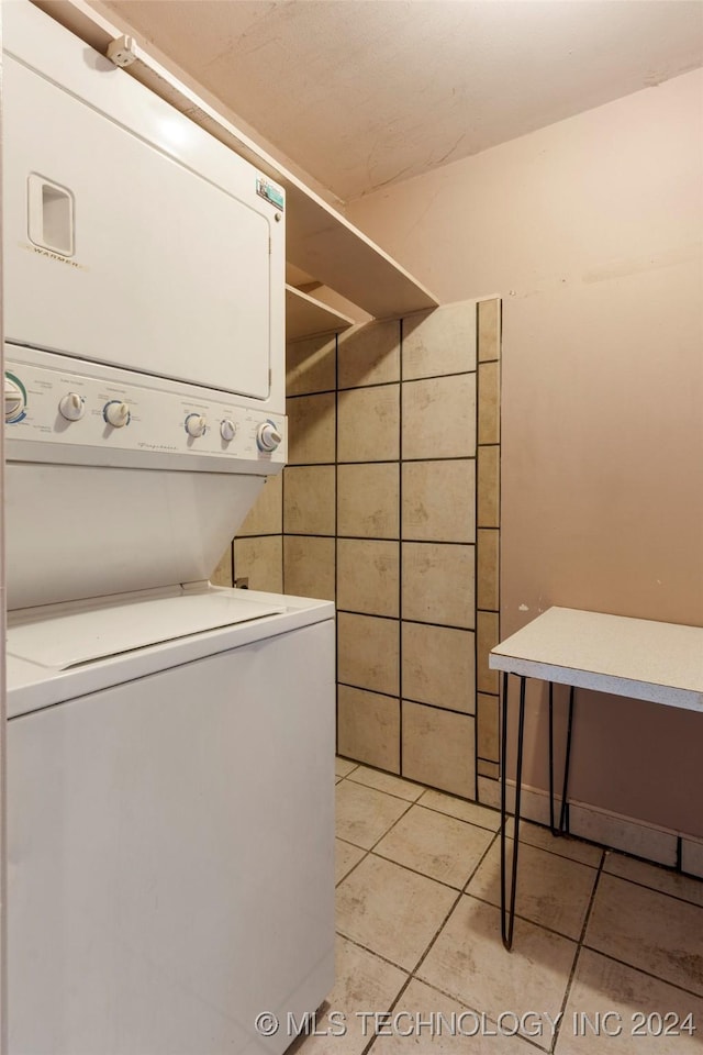 laundry area with tile walls, light tile patterned floors, and stacked washer / drying machine